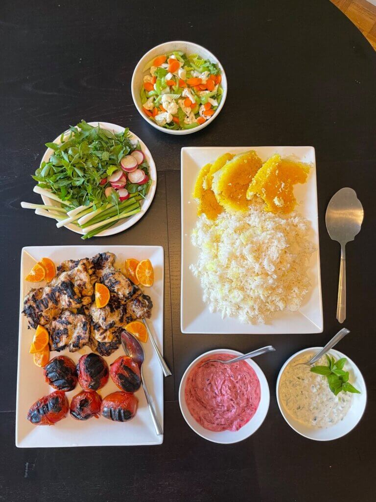 Top-down view of Persian Maast o Khiar served with grilled chicken, rice, fresh herbs, and yogurt dips