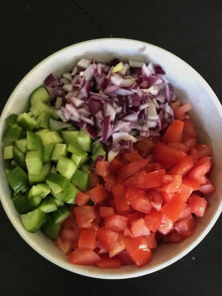 Fresh Salad Shirazi ingredients in a white bowl ready to be combined with chopped cucumber, tomato, and onion