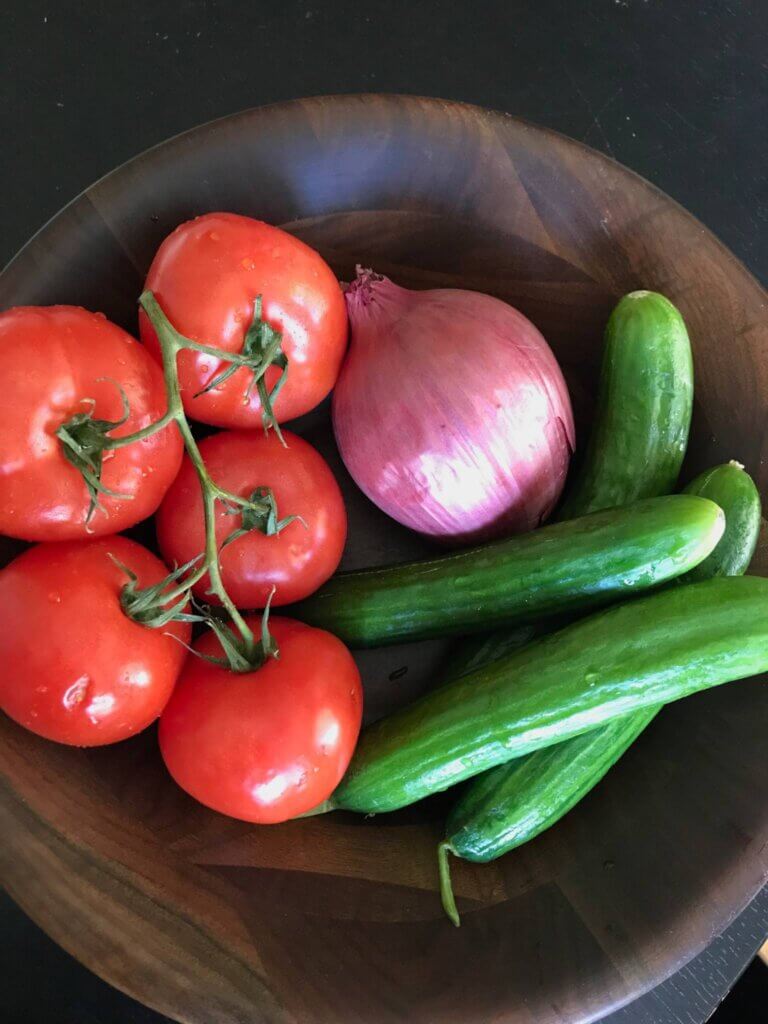 Fresh Salad Shirazi ingredients in a wooden bowl include cucumber, tomato, and onion