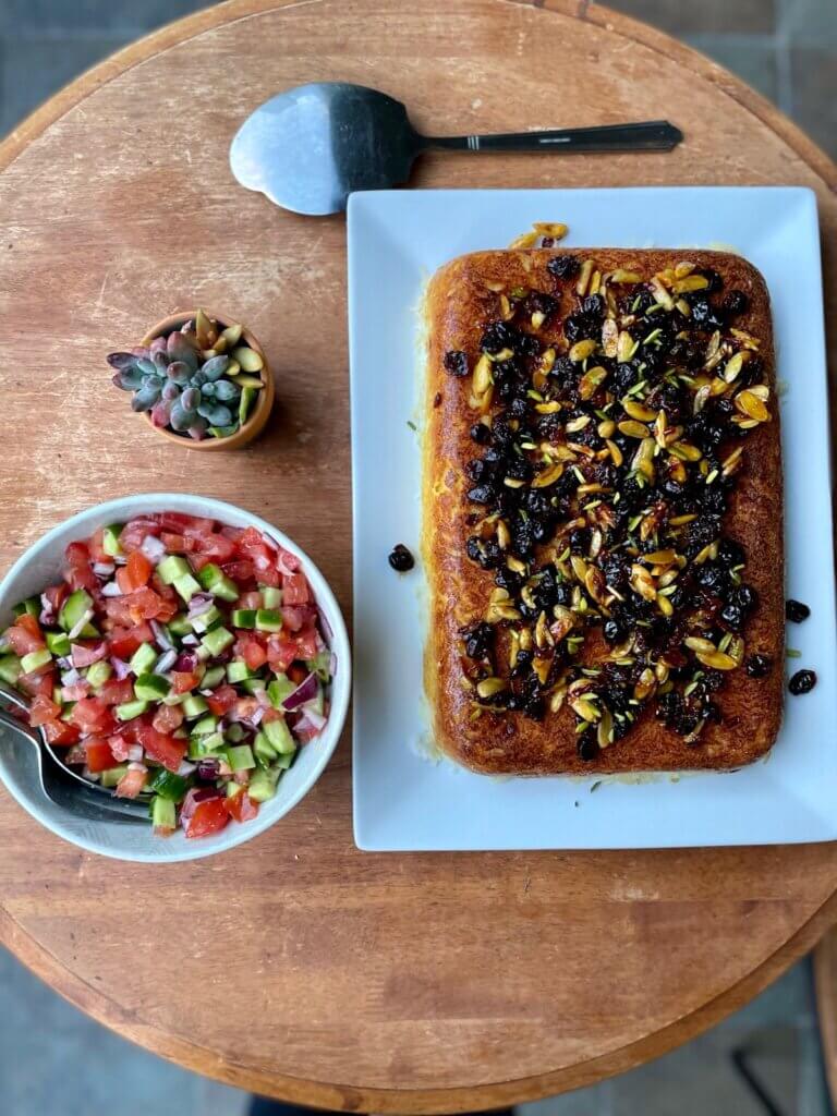 Traditional Persian dinner with golden Tahchin rice and Salad Shirazi on a wooden table