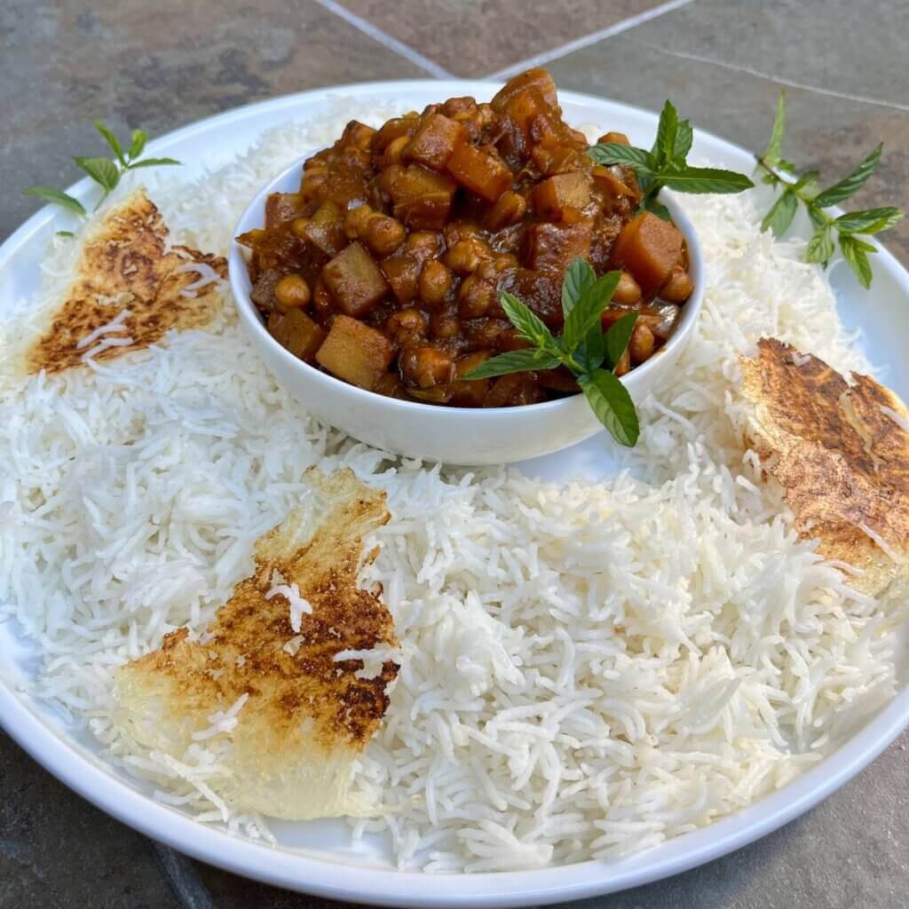 Close-up of Persian vegan Gheymeh made with chickpeas and potatoes, plated with saffron basmati rice and tahdig.