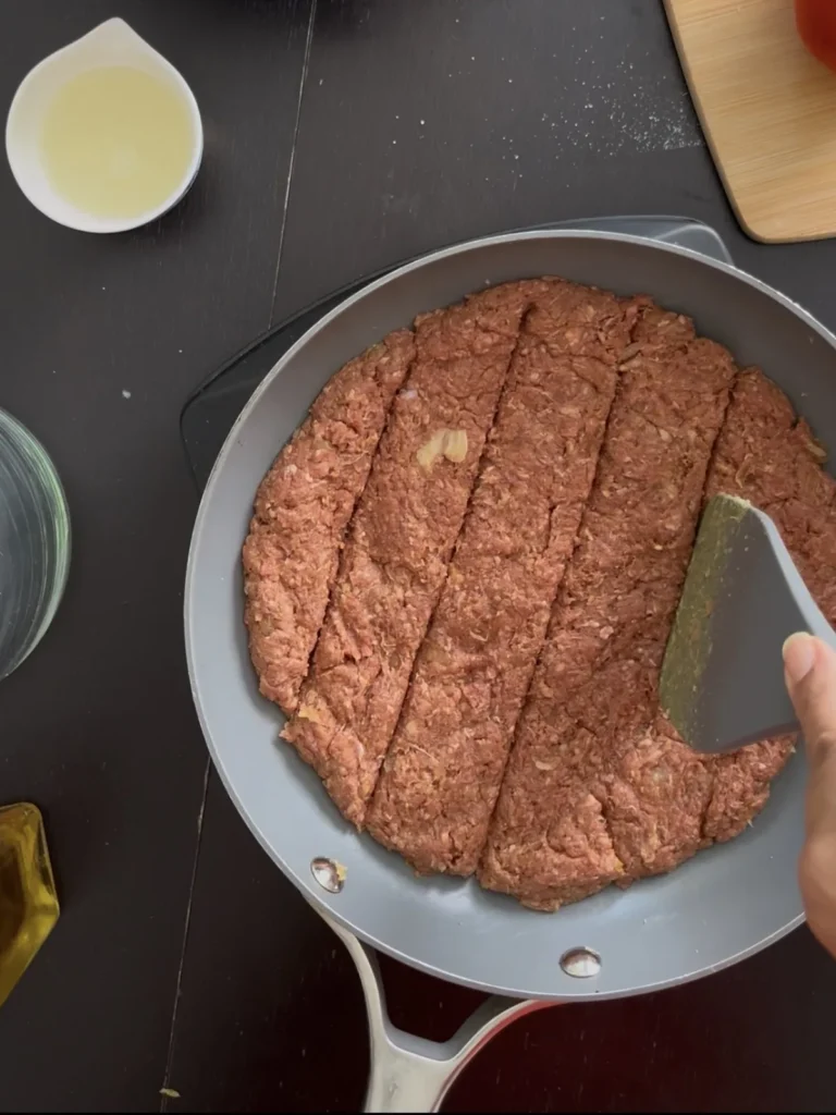 Persian kabab tabei mixture with grated onion cooking in a skillet