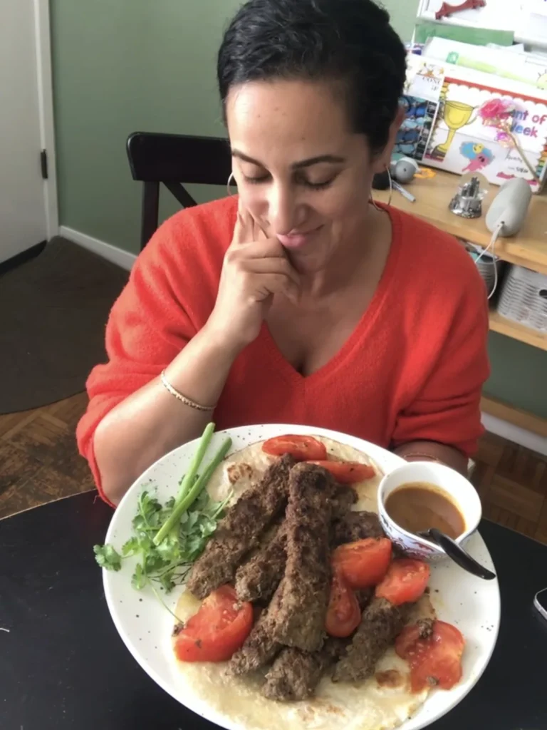 Home cook enjoying a platter of Persian pan kabab with tomatoes, herbs and flatbread